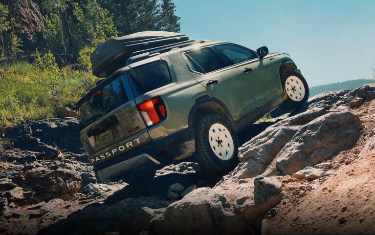 2026 Honda Passport TrailSport Elite in Ash Green Metallic back climbing a rocky off-road terrain (Mid-Size SUV). 2026 Honda Passport TrailSport Elite in Ash Green Metallic back climbing a rocky off-road terrain (Mid-Size SUV).