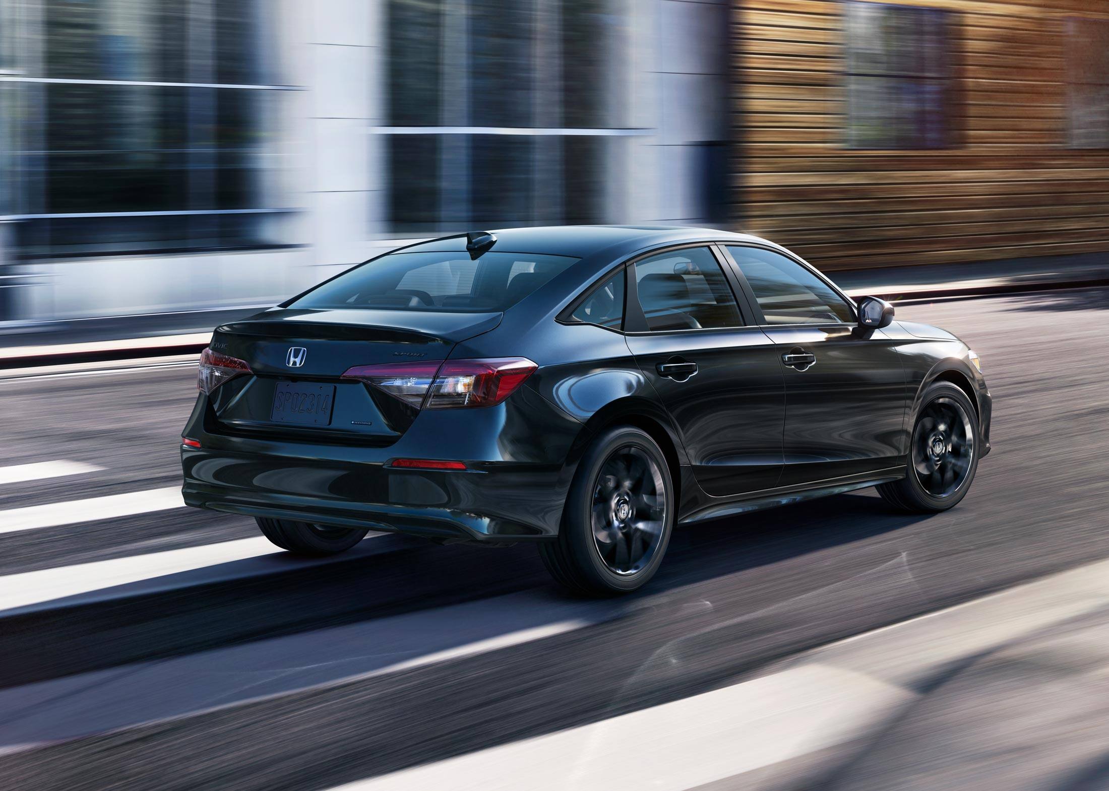 2026 Honda Civic Sedan Sport Hybrid in Crystal Black Pearl rear three-quarter view driving on a city street (Compact Sedan)
